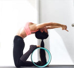 une femme utilise la roue de yoga confort vert d'eau sous les pieds avec le dos courbé