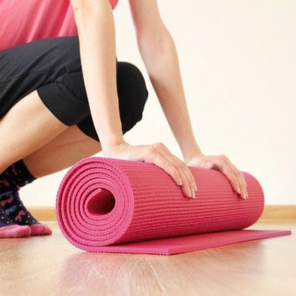 une femme roule un tapis d'exercices rose