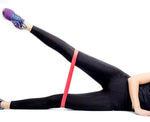 Une jolie femme utilise une bande élastique de résistance rouge pour crossfit, musculation, fitness, yoga, pilates.