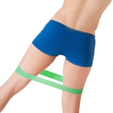 Une femme avec un joli booty utilise une bande élastique de résistance verte.