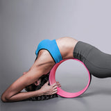 une femme utilise la roue de yoga confort rose dans son dos