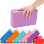 Une main porte une brique de Yoga confort disponible en plusieurs couleurs, anti-dérapante