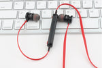 Écouteurs magnétiques Bluetooth AWEI T11 noir sidéral et rouge vif sur un clavier apple