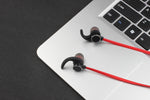 Écouteurs magnétiques Bluetooth AWEI T11 noir sidéral et rouge vif sur un clavier apple macbook