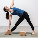 une femme utilise la brique de Yoga luxe hexagonale en liège pour faire ses étirements