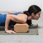 une femme utilise la brique de Yoga luxe hexagonale en liège naturel sous les épaules